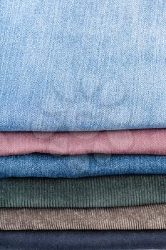 stack of various jeans and corduroys close up
