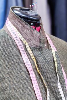 tailoring of male woolen tweed jacket on dummy and ready suits on background