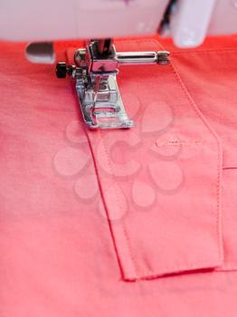 attaching pocket to red blouse on sewing machine close up