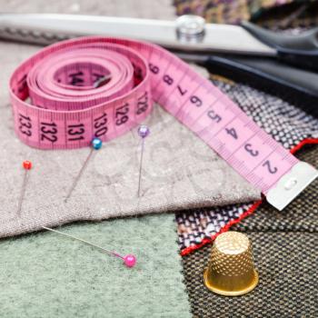 dressmaking still life - pink measuring tape, pins, thimble, shears on tissue