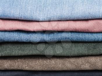 stack of various jeans and corduroy slacks close up