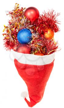 christmas gifts - xmas balls and decorations spillover from red santa hat on white background