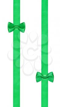 two little green bow knots on two parallel satin ribbons isolated on white background