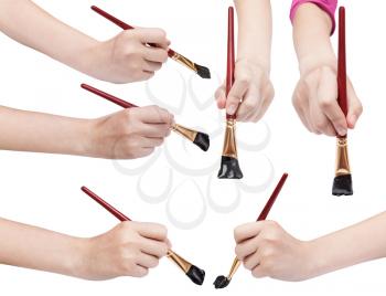 set of hands with flat art paintbrushes with black painted tips isolated on white background