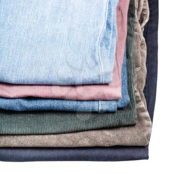 stack of different jeans and corduroys close up isolated on white background