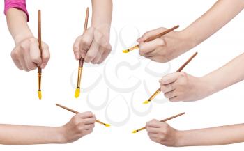 set of hands with round art paintbrushes with yellow painted tips isolated on white background