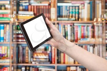 hand holds tablet pc with cut out screen and library on background