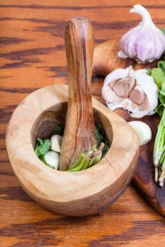 cooking seasonings - wooden mortar with cilantro herb and garlic on table