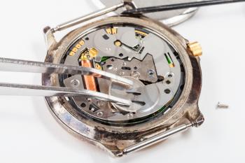 Repairing of watch - replacing battery in quartz watch by tweezers close up