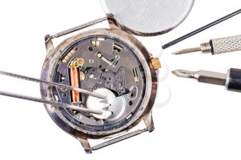 Repairing of watch - top view of replacing battery in quartz watch isolated on white background
