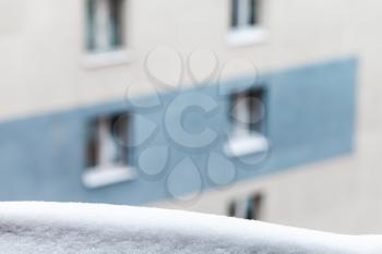 snow on windowsill and apartment house on background in cold winter day