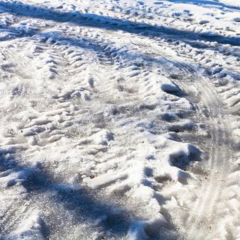 frozen car traces on snowy country road in cold winter day