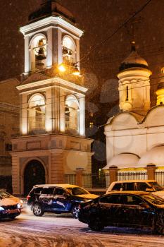 Sretenka street and tower of Church of the Trinity in Leaves in snowfall in Moscow in winter night