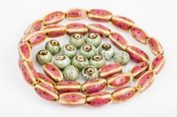 red oval and green round ceramic beads on white background