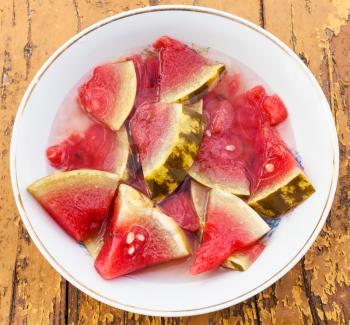 above view of pickled ripe watermelon on white plate on wooden table