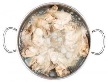 stewpan with cold boiled chicken wings in frozen greasy chicken bouillon isolated on white background