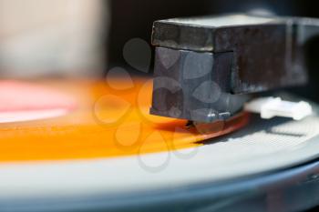 stylus of headshell on orange vinyl record close up