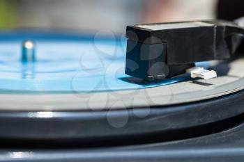 side view of headshell with stylus of turntable on blue flexi disc