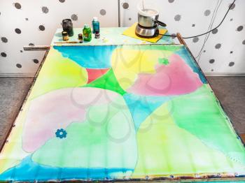 manufacturing steps of hot batik in the workshop - silk fabric with first layer of paints