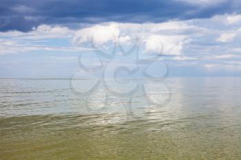 natural background - calm green water of Azov Sea and blue sky with white and rain clouds. Temryuk bay, Golubitskaya resort, Taman peninsula, Kuban, Russia