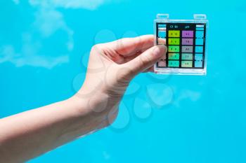 measure water pollution in blue outdoor pool by chemical tester