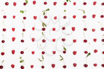 many raspberries and cherries arranged on white background