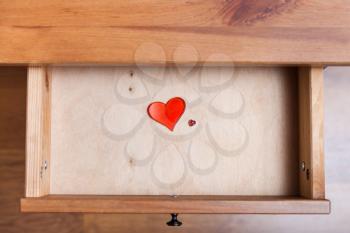top view of two red glass hearts in open drawer of nightstand