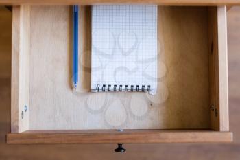 above view of modern pen and squared notebook in open drawer of nightstand