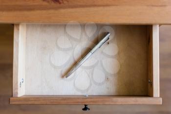 above view of old silver ballpen in open drawer of nightstand