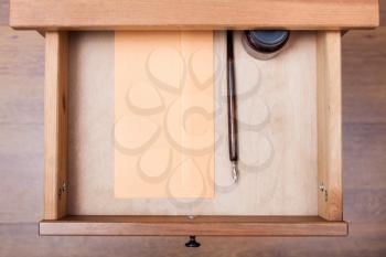 above view of nib pen, ink, paper envelope in open drawer of nightstand