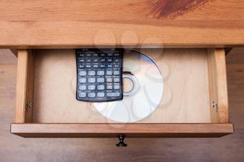 above view of scientific calculator and disk with the experimental data in open drawer of nightstand