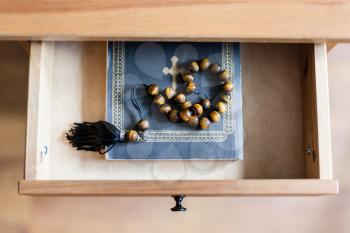 top view of rosary on Bible book in open drawer of nightstand