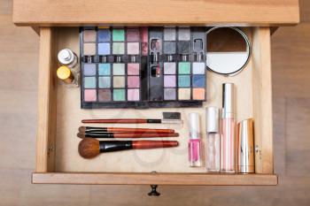 top view of makeup set in open drawer of nightstand