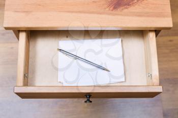 top view of folded note and pen in open drawer of nightstand
