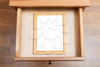 top view of simple picture frame with cut out canvas in open drawer of nightstand