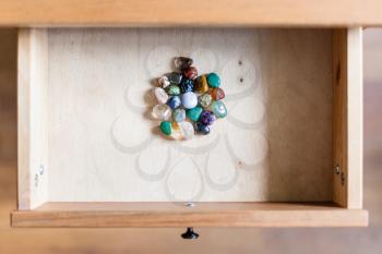 top view of pile of gemstones in open drawer of nightstand