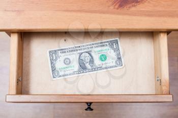top view of one dollar bill in open drawer of nightstand