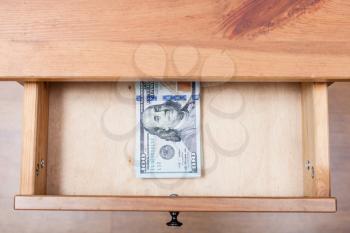 above view of hundred-dollar banknotes pack in open drawer of nightstand