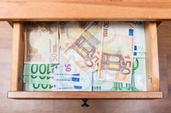 top view of many euro banknotes in open drawer of nightstand