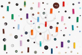 many spools of thread and various buttons on white background