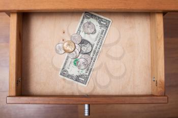 top view of one US Dollar and coins in open drawer of nightstand