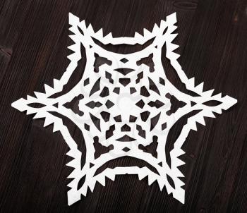 above view of snowflake cut out of paper on dark brown wood table