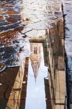 travel to Italy - tower of church Badia Fiorentina reflected in puddle on street after rain in Florence city