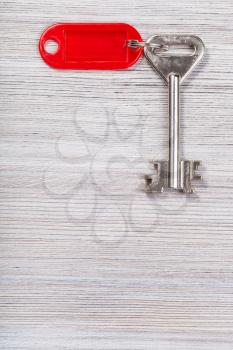 big door key with red blank key chain on wooden surface