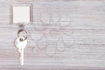 door key with white blank key chain on wooden surface