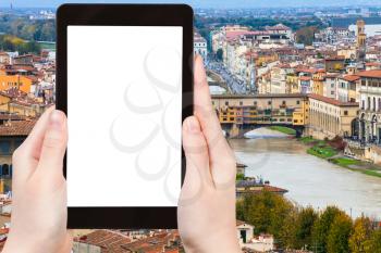 travel concept - tourist photographs ponte vecchio in Florence city on tablet with cut out screen with blank place for advertising in Italy