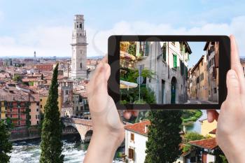 travel concept - tourist photographs street in Verona city on tablet in Italy
