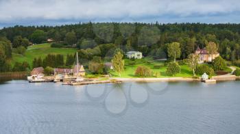 above view of homestead on green coast of Baltic Sea illuminated by sun in evening, Sweden