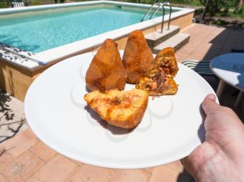travel to Italy, italian cuisine - traditional arancini ( fried rice filled balls with filling coated with breadcrumbs) on rural backyard in Sicily