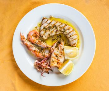 travel to Italy, italian cuisine - top view of various sicilian grilled fish and seafood on white plate in Sicily